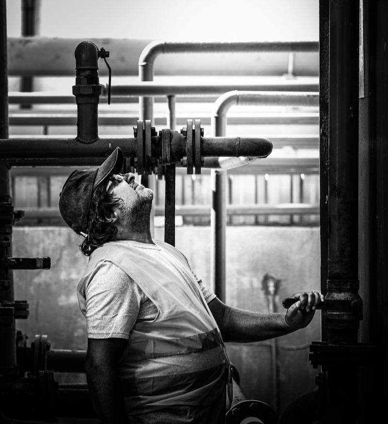 A plumber looking up at a run of pipes and valves