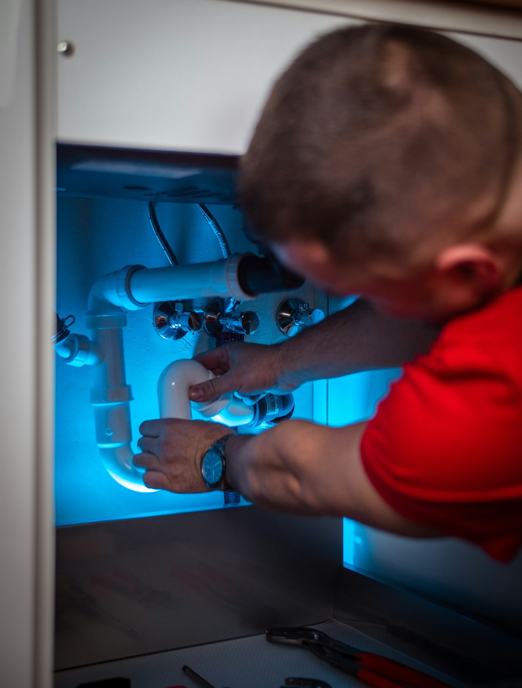 Plumber fixing the drain pipes under a kitchen sink